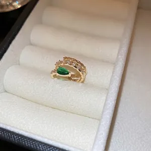 Gold plated snake wrap ring featuring a pear-cut green zircon and shimmering micro-pavé diamonds