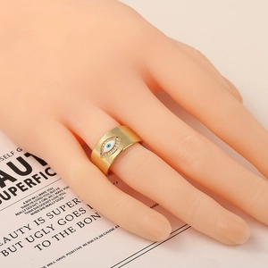Detail of wide gold plated evil eye ring with micro-paved cubic zirconia accents