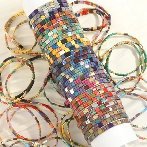 Detailed view of colorful Tila bead stretch bracelets and colorful enamel tile jewelry
