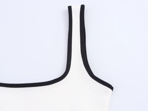 Detail of white knit dress featuring contrast black piping and fine stitching texture