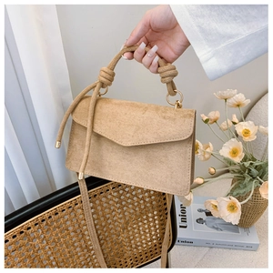 Detail of khaki suede mini square bag with woven handle and elegant gold ring closure