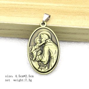 Vintage bronze Saint Anthony oval keychain pendant on light wood and white surface