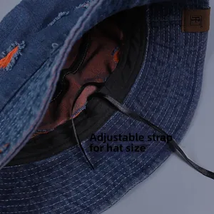 Detail of blue denim bucket hat interior with orange lining and black adjustable drawstring