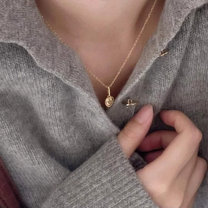 Close-up of a 925 silver heart necklace on a grey sweater for daily style