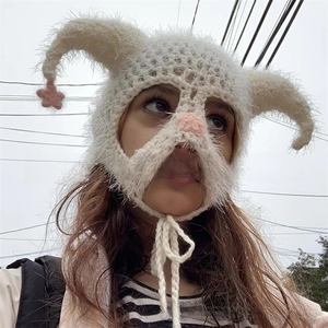 Outdoor view of a creative white knit monster hat with horns and pink star details