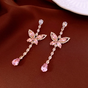 Detailed view of pink butterfly earrings with water drop pendants on dark silk