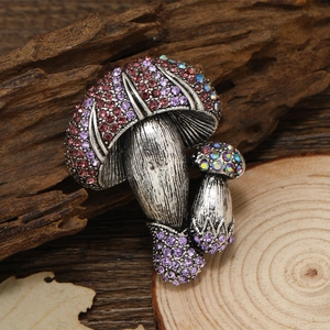 Vintage zilveren paddenstoel broche met paarse en roze strass op een bos hout ondergrond