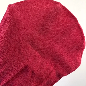 Macro detail of the red Moroccan exfoliating bath glove showing coarse grain texture
