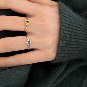 Detail of silver and gold floral rings with black gemstones on a hand