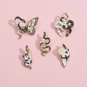Set of five mystical snake enamel pins in black and white with gold finish on pink background