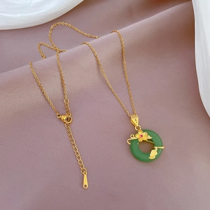 Detail of flower-shaped green jade pendant on gold necklace over purple silk fabric