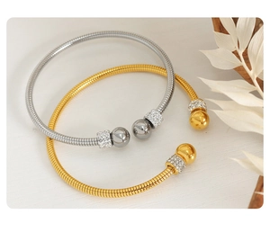 Detailed view of gold and silver snake texture bracelets with sparkling crystal beads