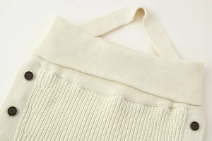 Detail of ivory knit top showing ribbed texture and vintage brown button closure