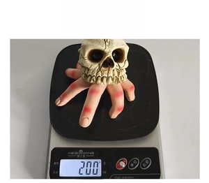 Detailed view of scary resin skull on severed hand prop showing product weight of 200g