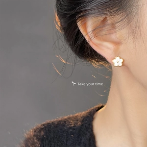 Close-up of golden clover earrings with white mother of pearl inlay on model