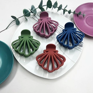 Close-up of four matte shell-shaped hair claws in purple, navy, green and burgundy