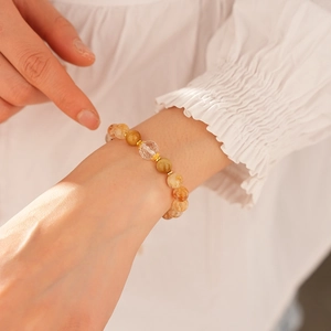 Detailed macro view of beaded bracelet with quartz stones and gold gear spacers on wrist