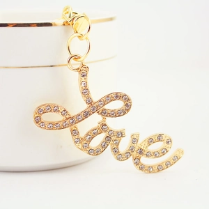 Sparkling gold metal LOVE keychain with rhinestones and lobster clasp on white background