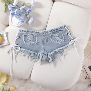 Dettaglio degli shorts in denim azzurro con bordi sfrangiati e lacci laterali intrecciati