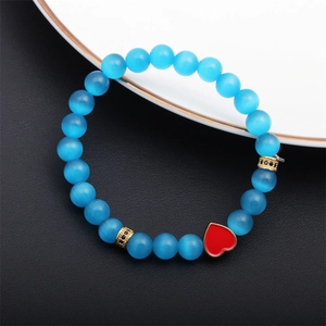 Close-up of blue cat-eye stone beads with red heart charm and golden crystal spacers
