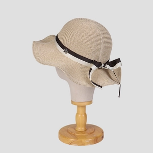 Close-up of beige straw hat with black-and-white ribbon bow and silver flower buckle detail