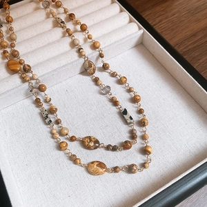 Detail of bohemian seashell beaded necklace with natural stone textures in a black jewelry box