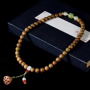 Detail of wooden prayer beads with lotus seed pod pendant on blue display box