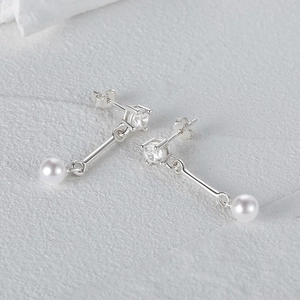 Detailed view of silver asymmetric pearl tassel earrings with cubic zirconia accents