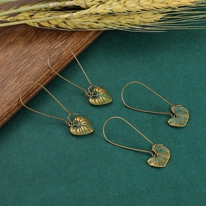 Détail de boucles d'oreilles feuilles en bronze vintage avec patine verte sur bois rustique