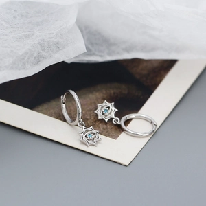 Macro shot of silver devil eye earrings with blue cubic zirconia and star accents