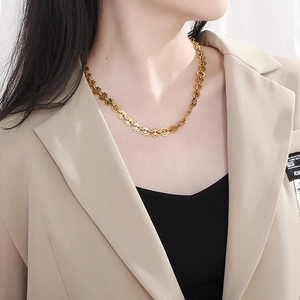 Goldene Titanstahl-Sonnenblumenkette, getragen von einem Model im beigen Sakko