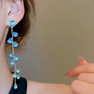 Close-up of elegant leaf tassel earrings with blue zircon water drops on a model