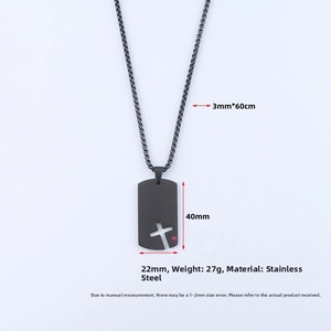 Detail of matte black stainless steel cross dog tag with a small red gemstone accent