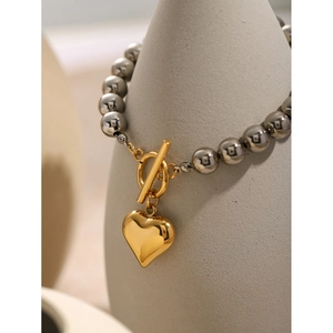 Détail du pendentif cœur en or 18k et du fermoir OT sur un bracelet en perles