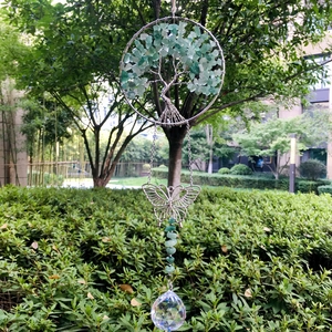 Close-up of wire-wrapped tree of life with green crystals and a crystal prism ball