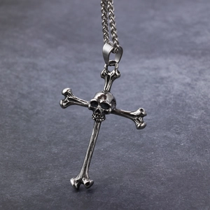 Gothic punk silver skull cross pendant necklace with dark metal chain on rock texture