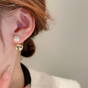 Close-up of double-sided earrings with white faux pearl and gold mirror metal ball