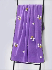 Detail of purple coral fleece towel with white daisy embroidery and green wavy edges