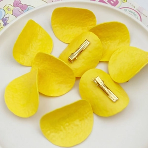 Realistic yellow potato chip hair clips made of resin on a white ceramic plate