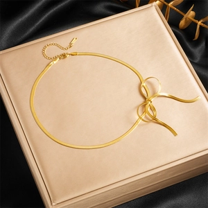 Elegant gold plated stainless steel bow necklace on a snake chain displayed over a gift box