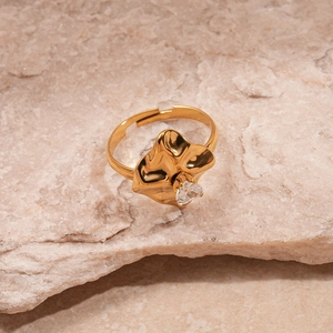 Detail of gold wavy leaf ring featuring a white zircon on a natural stone background
