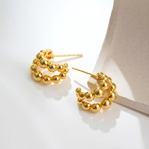 Detail view of 18K gold plated double-layer bubble ball hoop earrings on a stone base