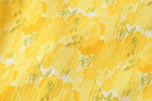 Close-up of yellow floral seersucker fabric texture and delicate printed pattern