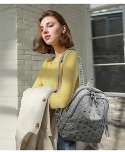 Detail of grey vintage leather backpack with silver rivets shown on person