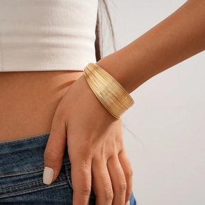 Close-up of stacked gold multi-layer wide wire cuff bracelet on a female wrist