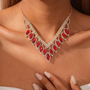Detail of V-shaped gold necklace with red marquise gems and rhinestones on model