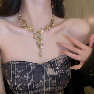 Detailed view of luxury gold necklace with teardrop crystals worn by a model