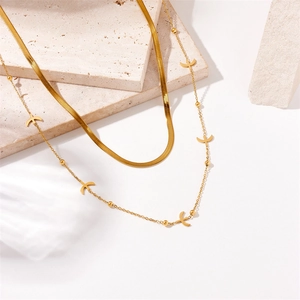 Detail of layered gold necklaces with snake chain and crescent pendant on stone