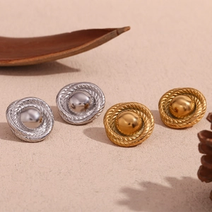 Macro shot of gold and silver textured button earrings with twisted borders on beige base