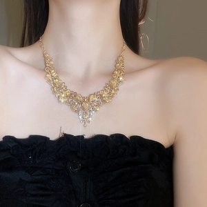 Close-up of sparkling gold V-shape necklace with yellow crystals worn by a model